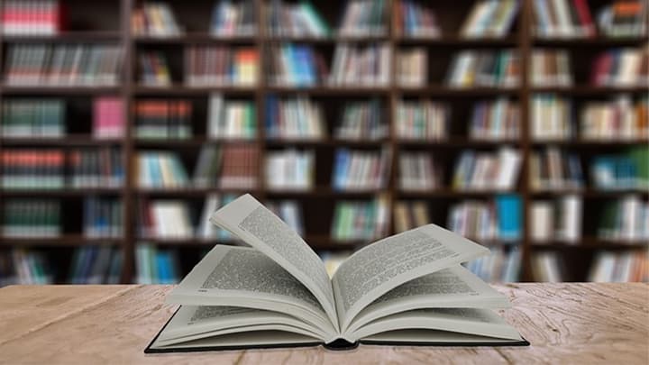 Open book on the background of shelves with books